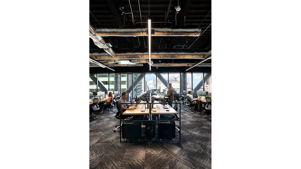 A group of people sitting at desks in a room with windows.