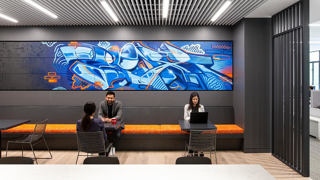 A group of people sitting at a table in front of a large screen.