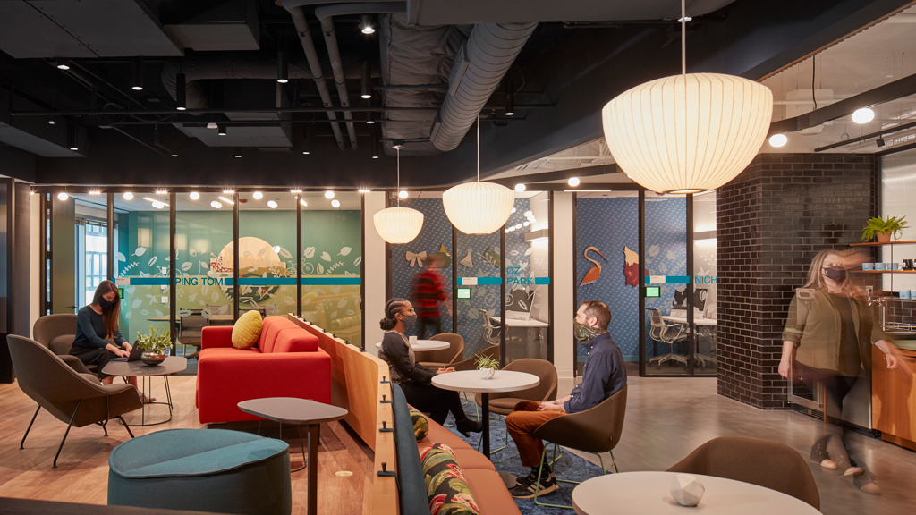 A group of people sitting in a room with a large screen.