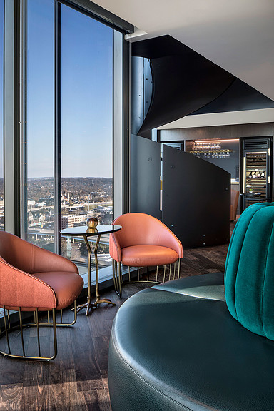 A room with a table chairs and a window with a view of a city.