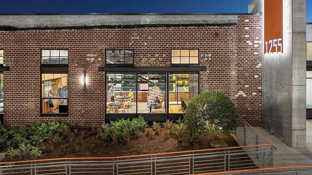 A brick building with a patio and a patio with plants and a fence.