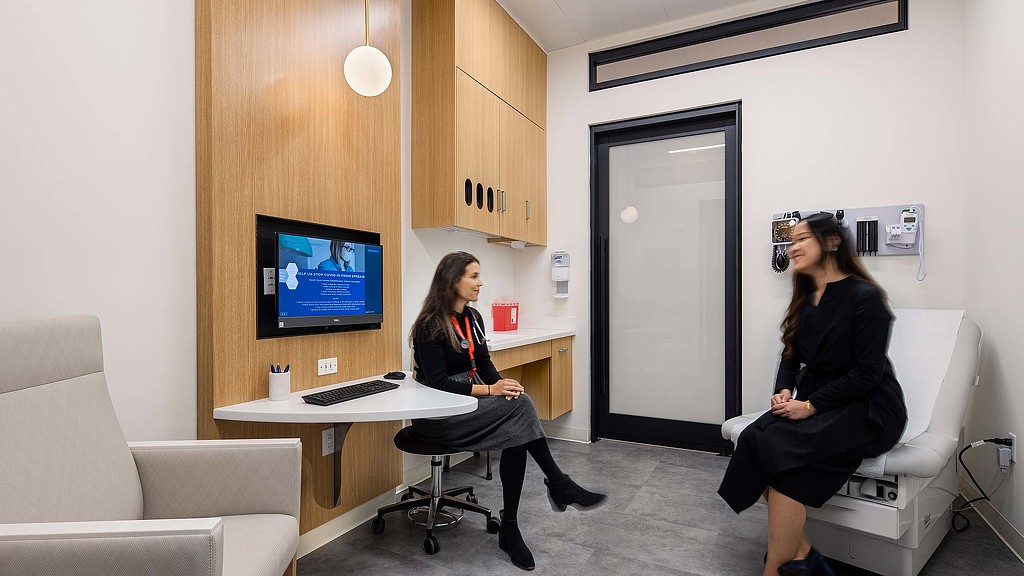 A couple of women sitting at a desk in a room with a computer.
