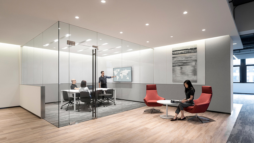 A group of people sitting in a room with a table and chairs.
