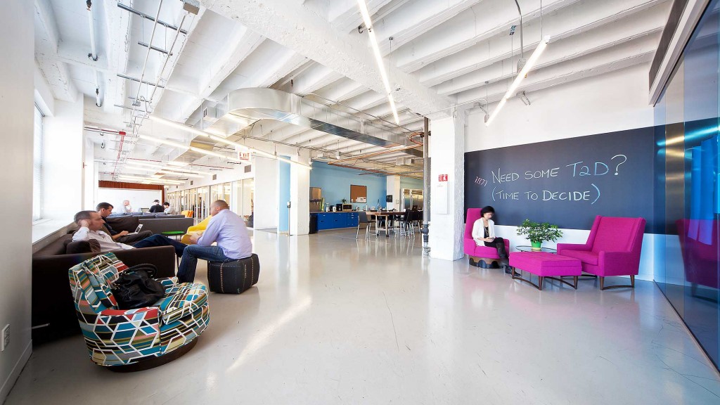A group of people sitting in a room with a large screen.
