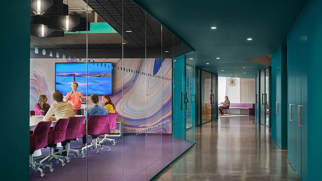 A group of people sitting in a room with a large screen.