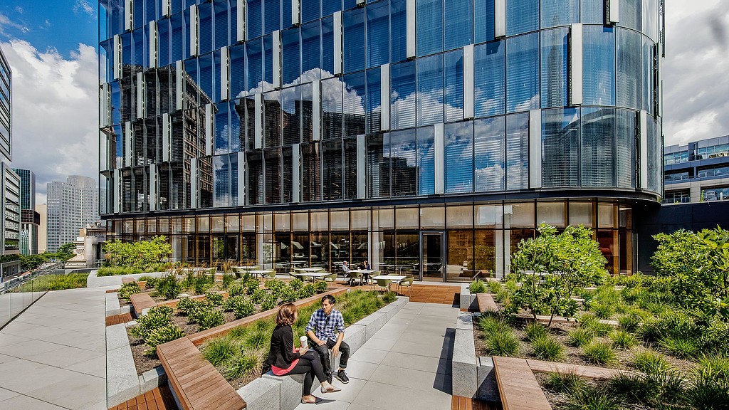 A couple sitting on a bench outside a building.