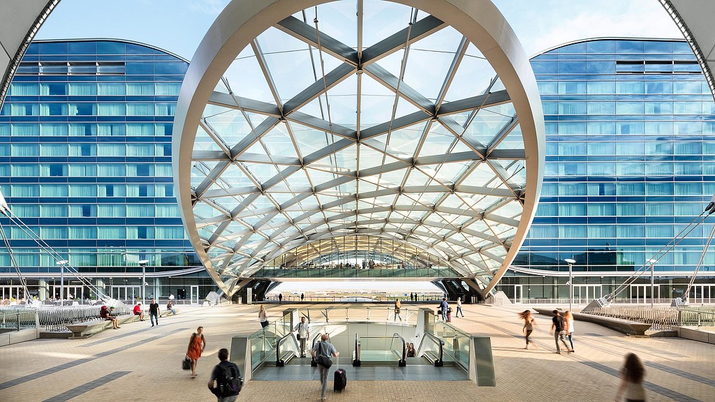 A large glass building with people walking around.