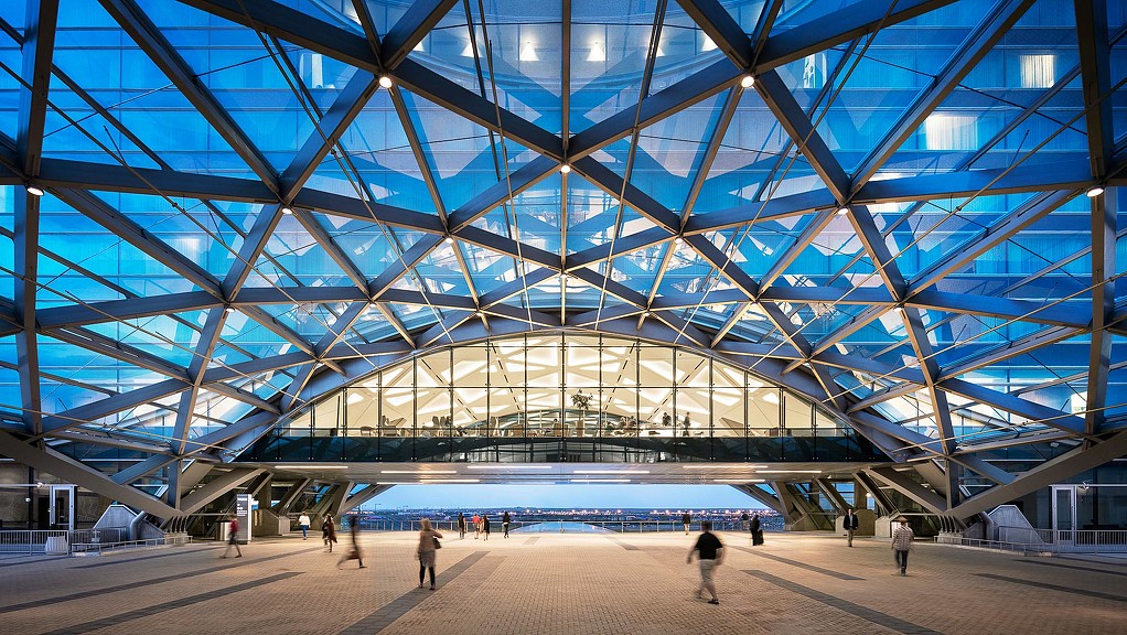 A large glass building with people walking around.