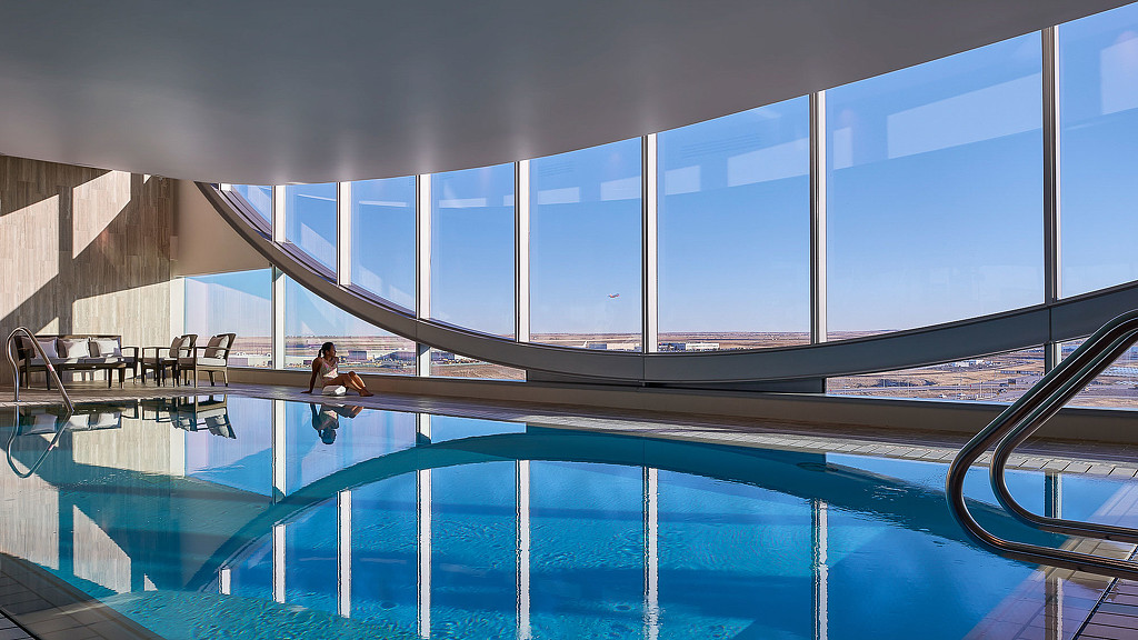 A person sitting on a ledge above a pool.