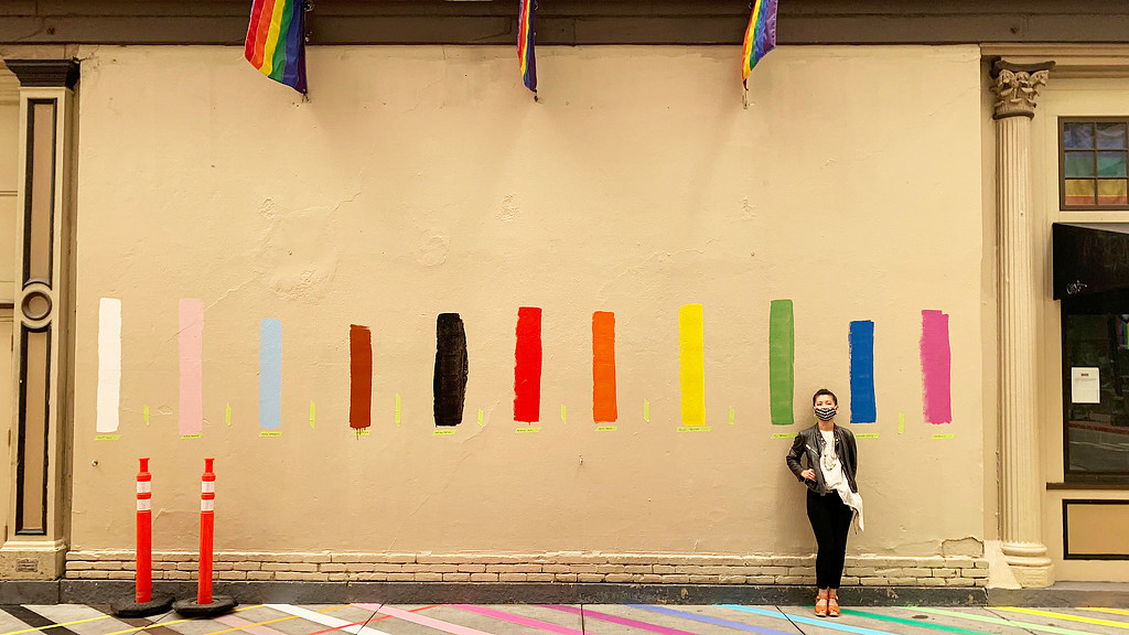 A person standing in front of a building with flags.
