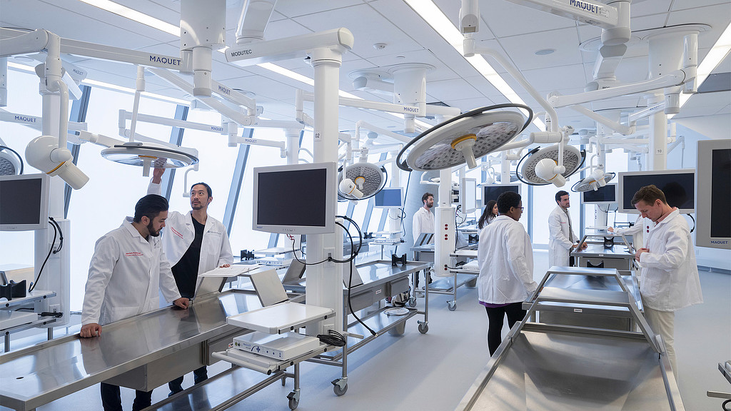 A group of people in white coats in a room with computers.