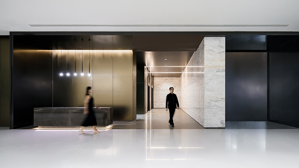 A man and woman walking in a large room with white walls.