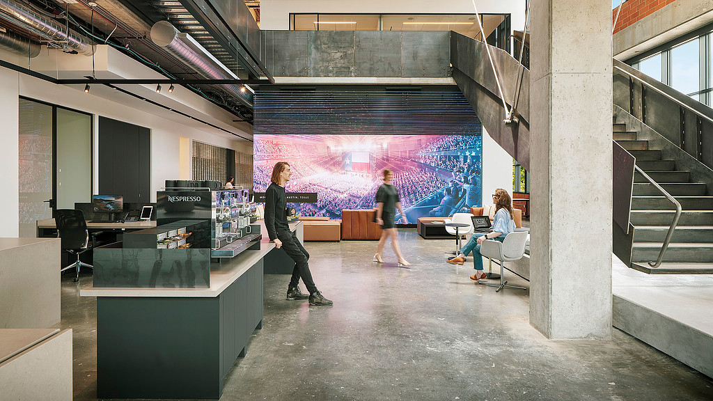 People in a room with a large screen.
