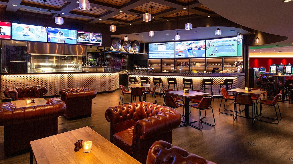 A room with tables and chairs and a large screen with lights.