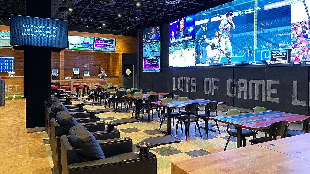 A room with a large screen and chairs and tables.