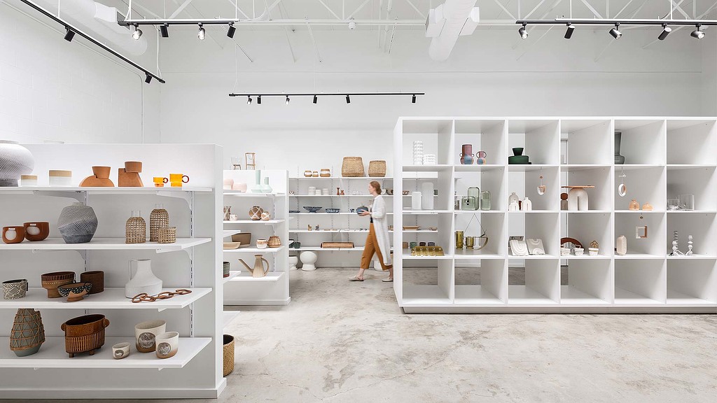A person standing in a room with shelves and white shelves.