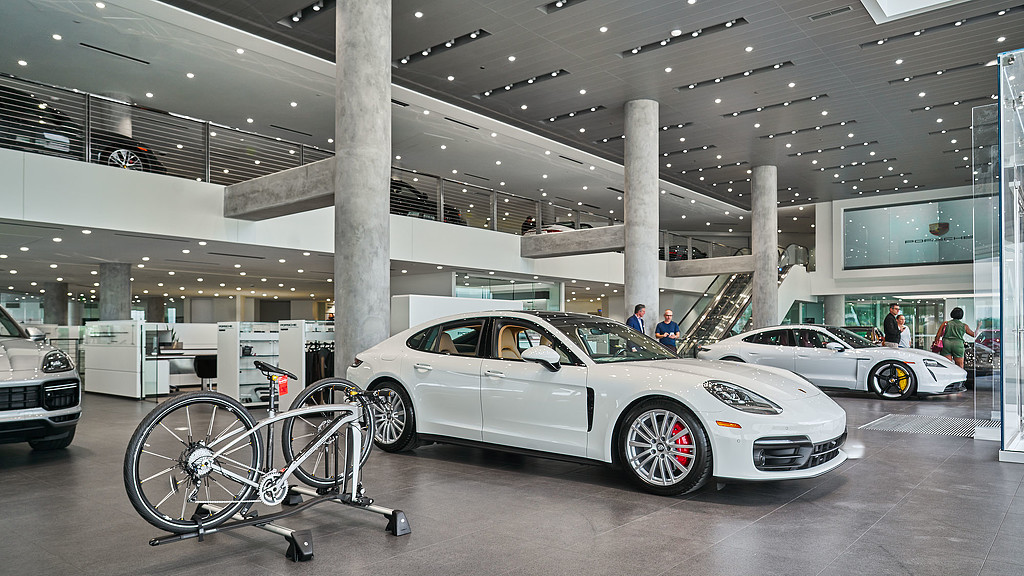 A white car with a wheel on the rim in a showroom.