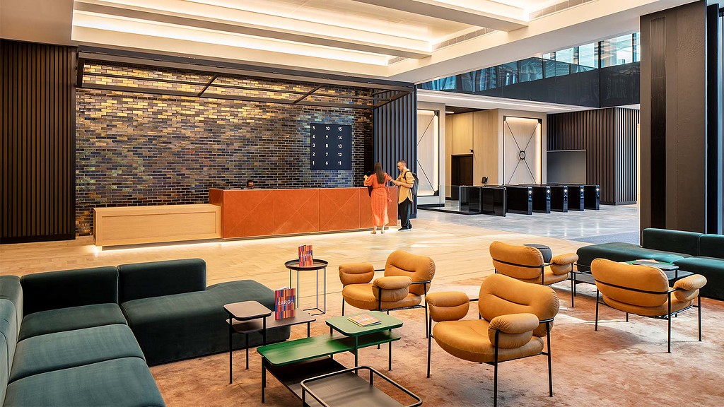 A couple of people standing in a room with chairs and tables.