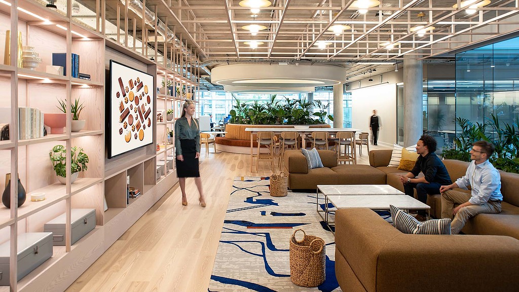 A person standing in a room with people sitting on couches.