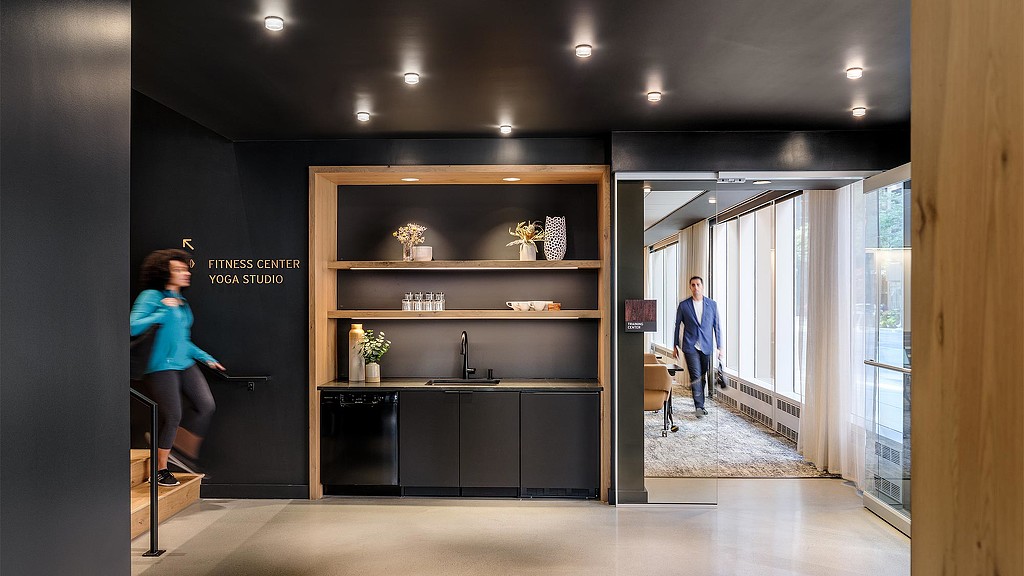 A woman in a room with a man and a woman in the background.