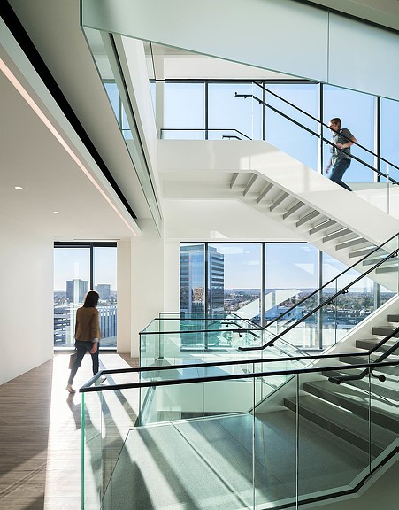A couple of people walking up a staircase in a building.