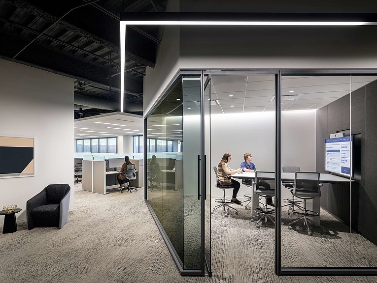 A group of people sitting at a table in a room with glass walls.