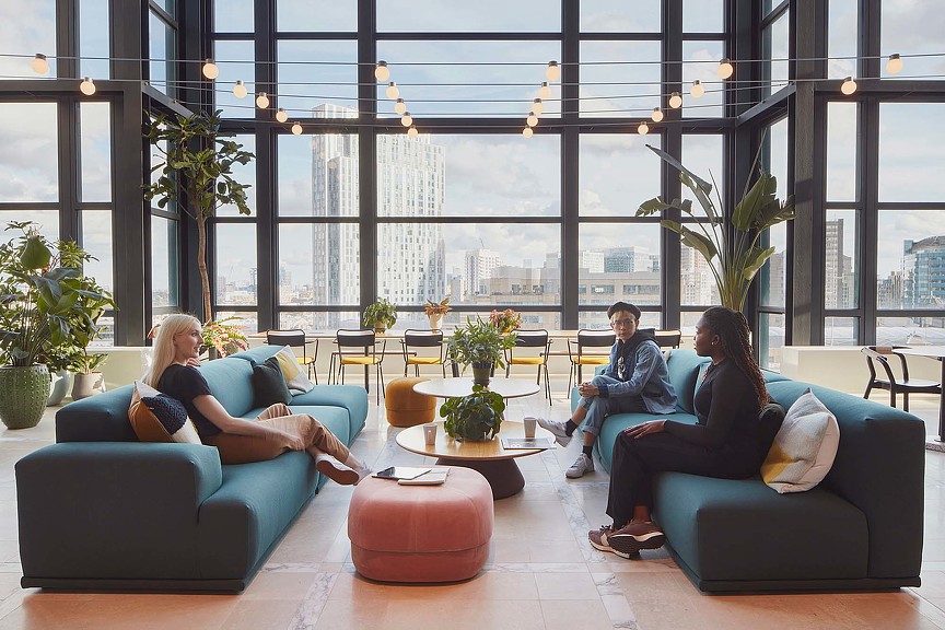 A group of people sitting on couches in a room with large windows.
