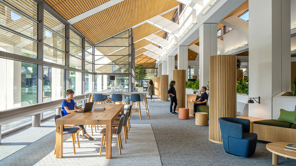 People sitting at tables in a large room with windows and a large glass ceiling.