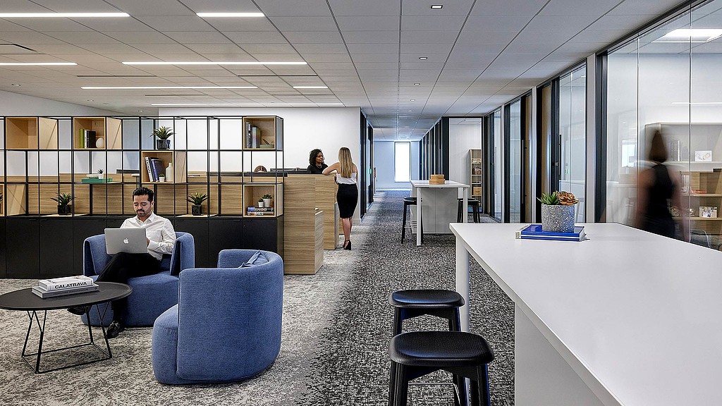 A man sitting in a chair in a room with a woman standing.