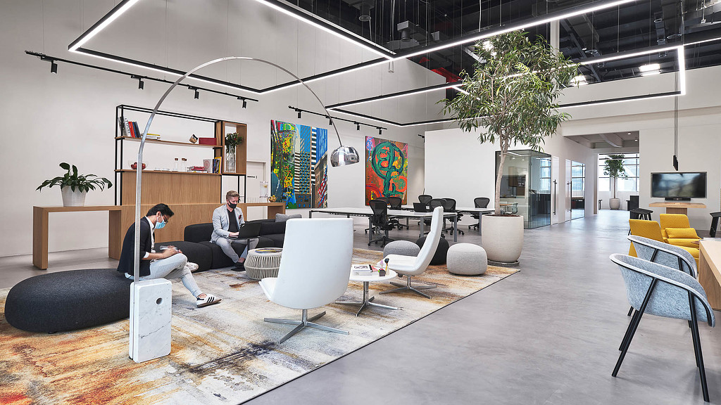 A man and woman sitting on a couch in a room with a large glass ceiling.