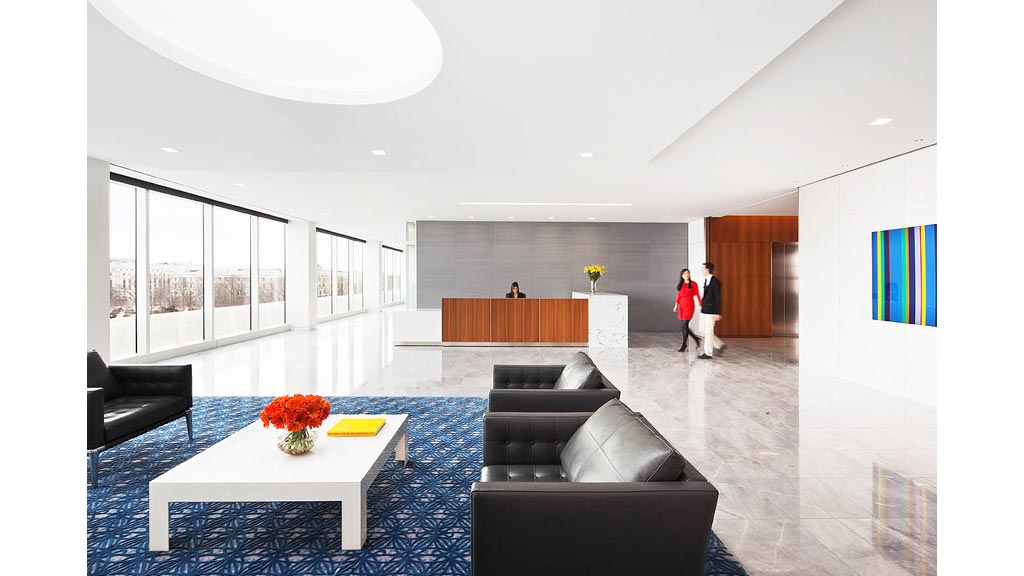 A man and woman walking in a large room with a large window.