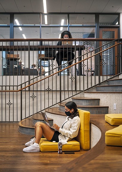 Close-up of female student studying on yellow cushions and another female student studying on raised table
