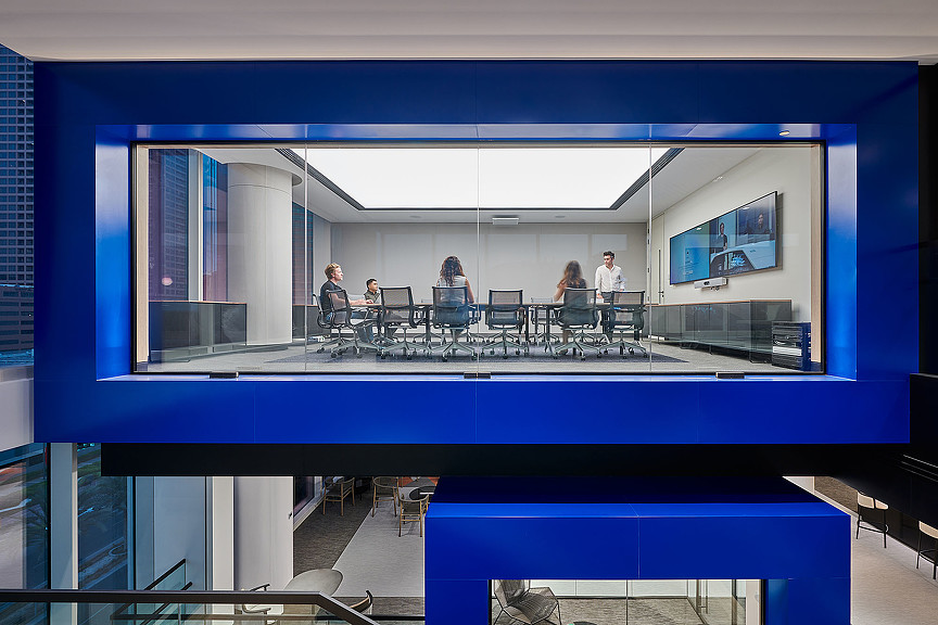 A group of people sitting at a table in a room with windows.