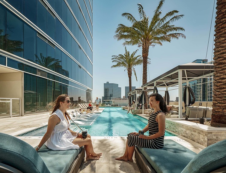 2 women sitting by Aspire Post Oak luxury apartment pool