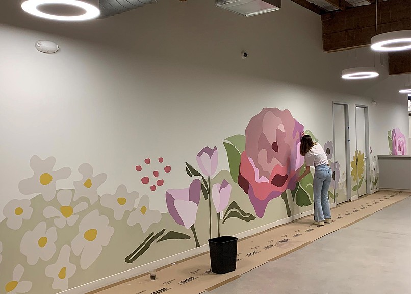 Volunteer painting Rose Haven Community Day Shelter floral mural
