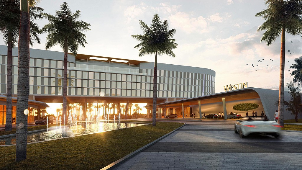 A building with palm trees and a road in front of it.