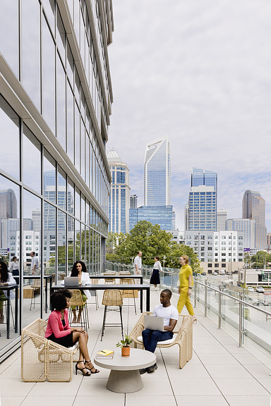 A group of people sitting on a deck overlooking a city.