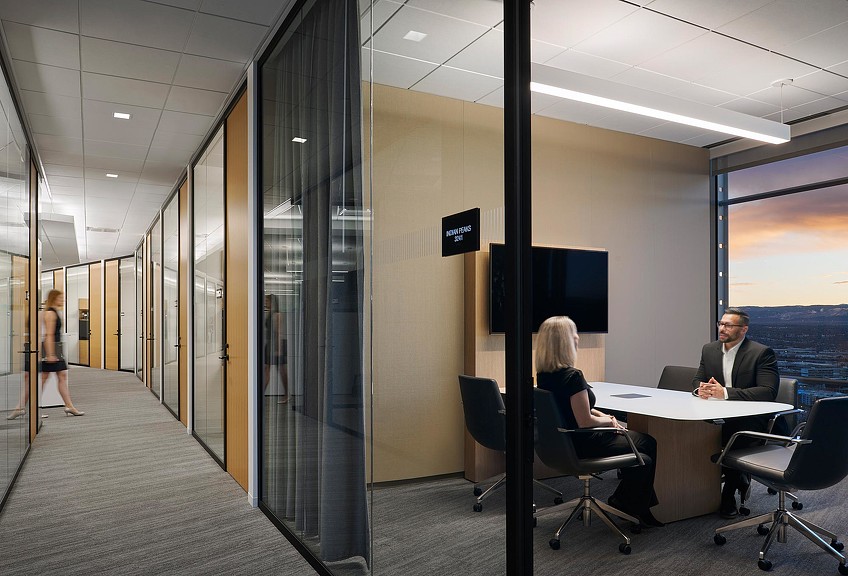 A man and a woman sitting at a table in a room with a large window.