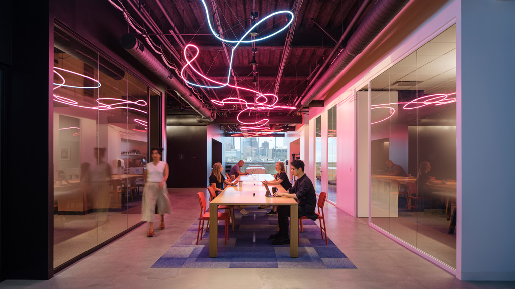 A group of people sitting at a table in a room with pink walls.