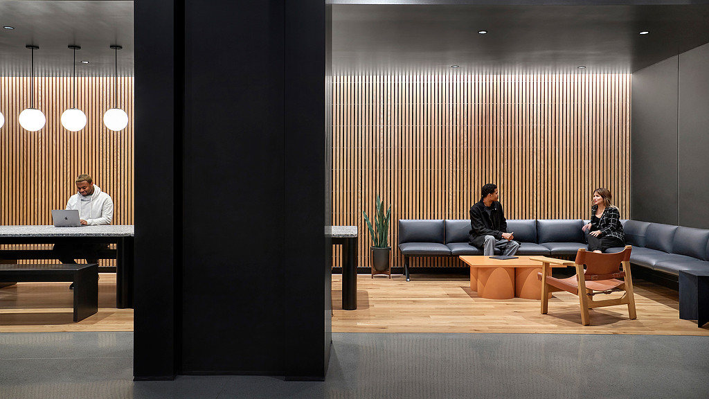 A group of people sitting on a couch in a room with a large screen.