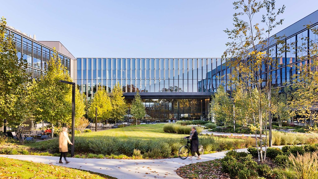 Exterior daytime image of 225 Wyman with trees, a walking trail and outdoor seating