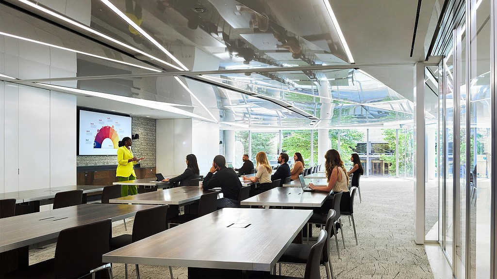 A woman giving a presentation to a room of 8 people.