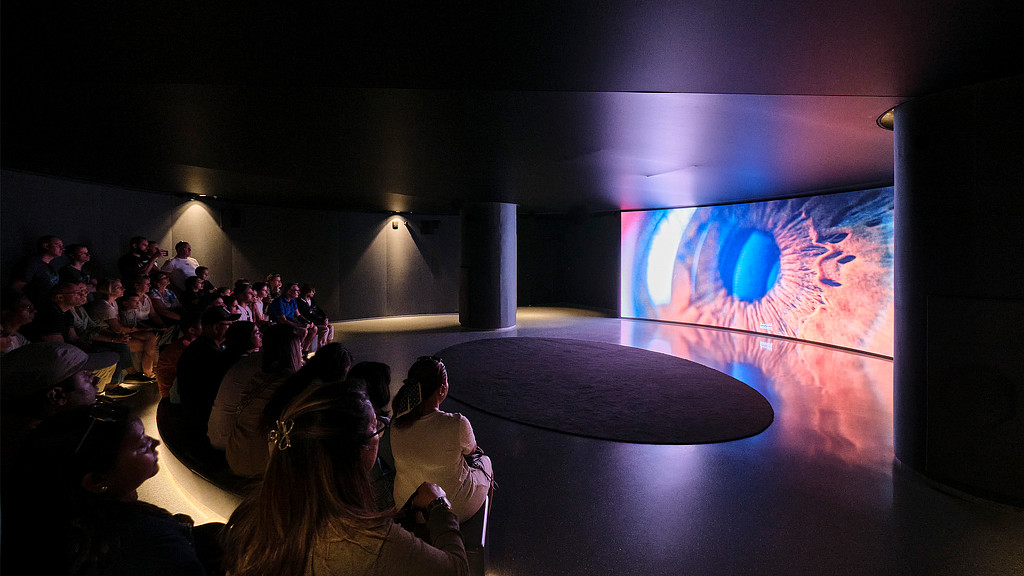 A group of people sitting in a room with a large screen.