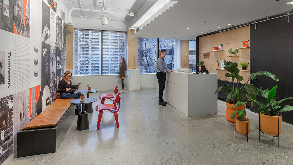 A man standing in a room with a woman sitting at a table.