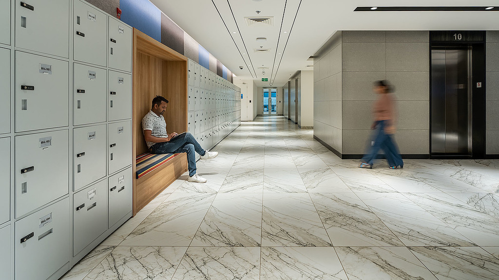 A person sitting on a bench in a room with lockers.