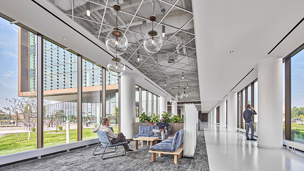 Hallway with large windows on either side and glass pendants above casual seating