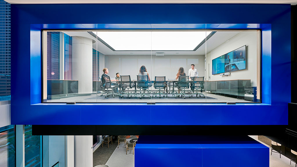 A group of people sitting at a table in a room with windows.