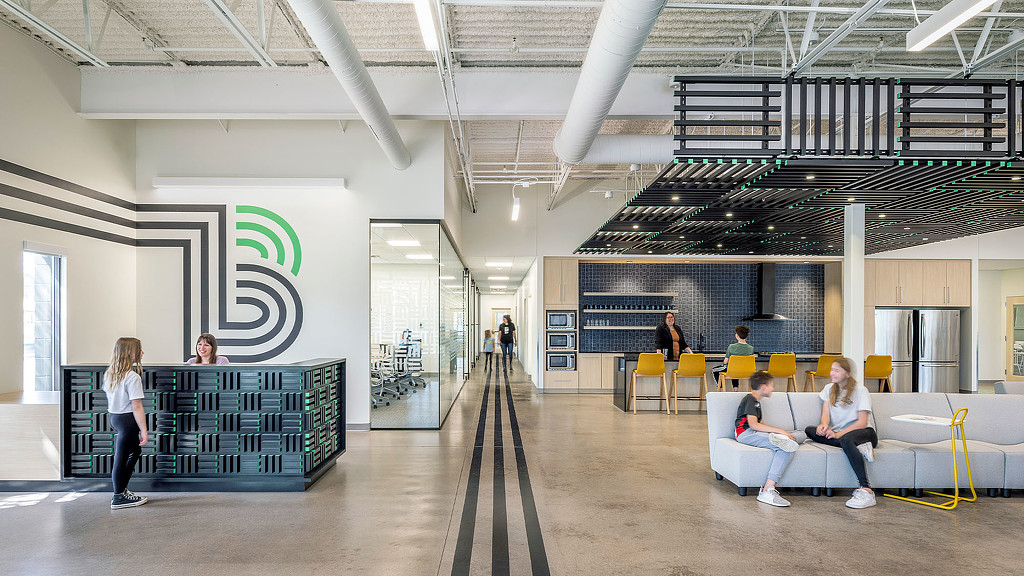 A group of people sitting on a bench in a large room.