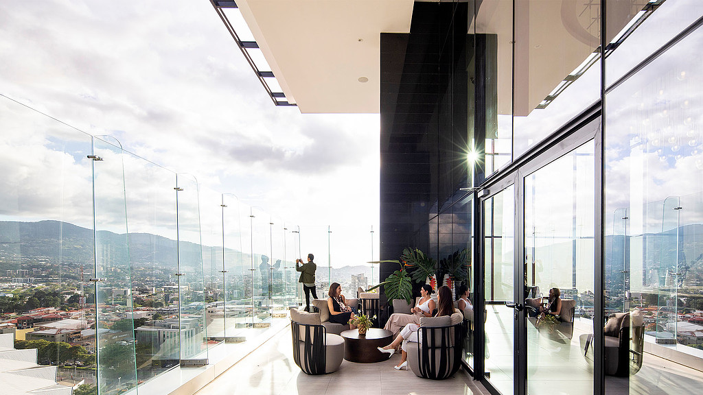 A group of people sitting on a balcony overlooking a city.