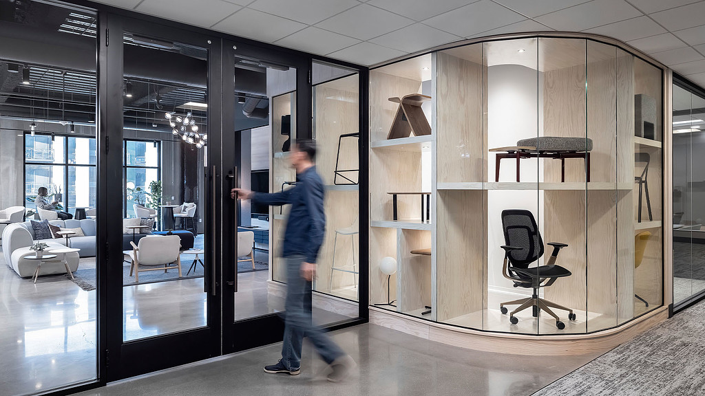 A showroom wall in a modern office with a seating area behind glass walls